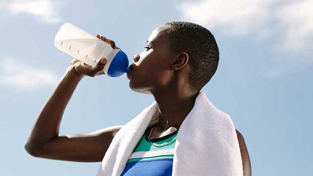 Athlete drinks from her water bottle